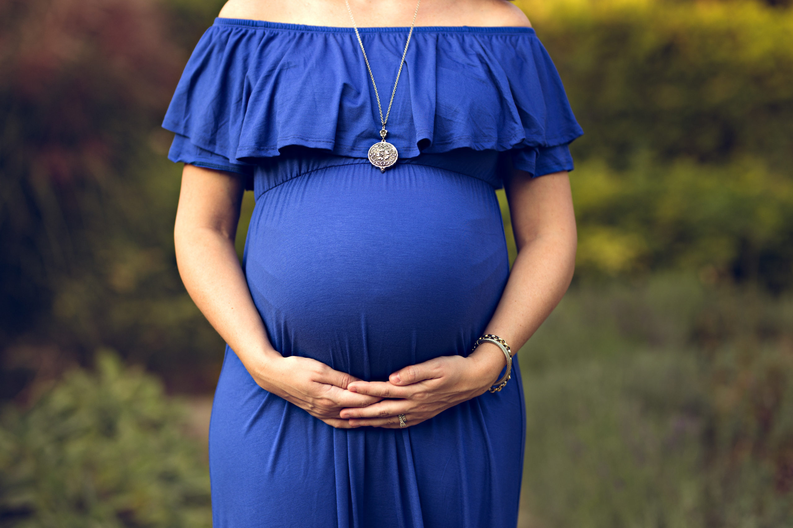 Toronto Prenatal Massage - close up of pregnant belly in blue dress