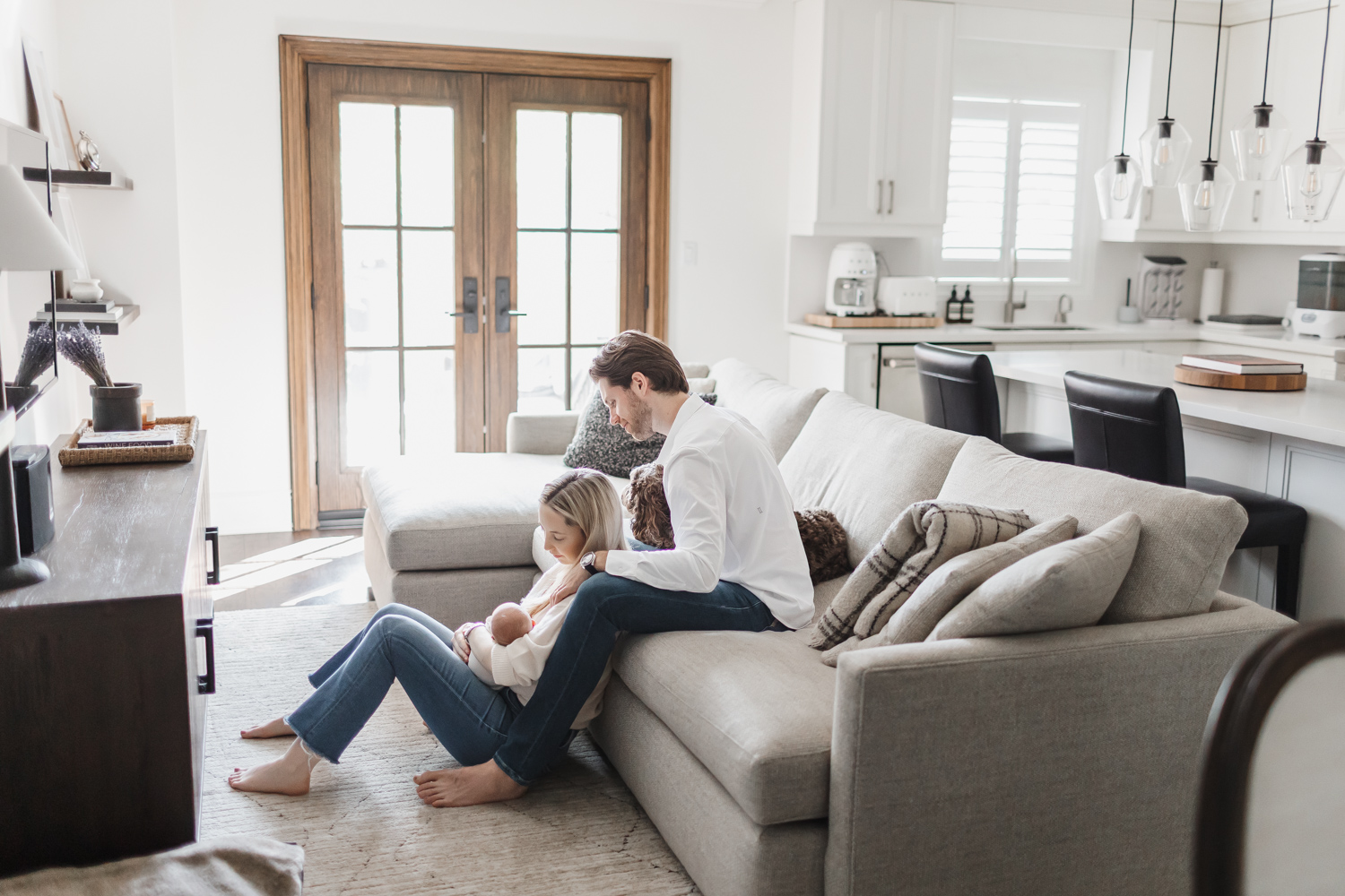 Couple and newborn relaxing in living room of Toronto home during newborn photos