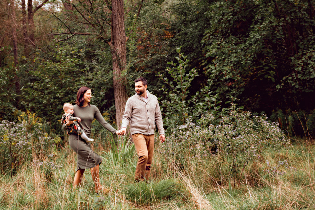 couple and baby walking in wooded park 1 of 1