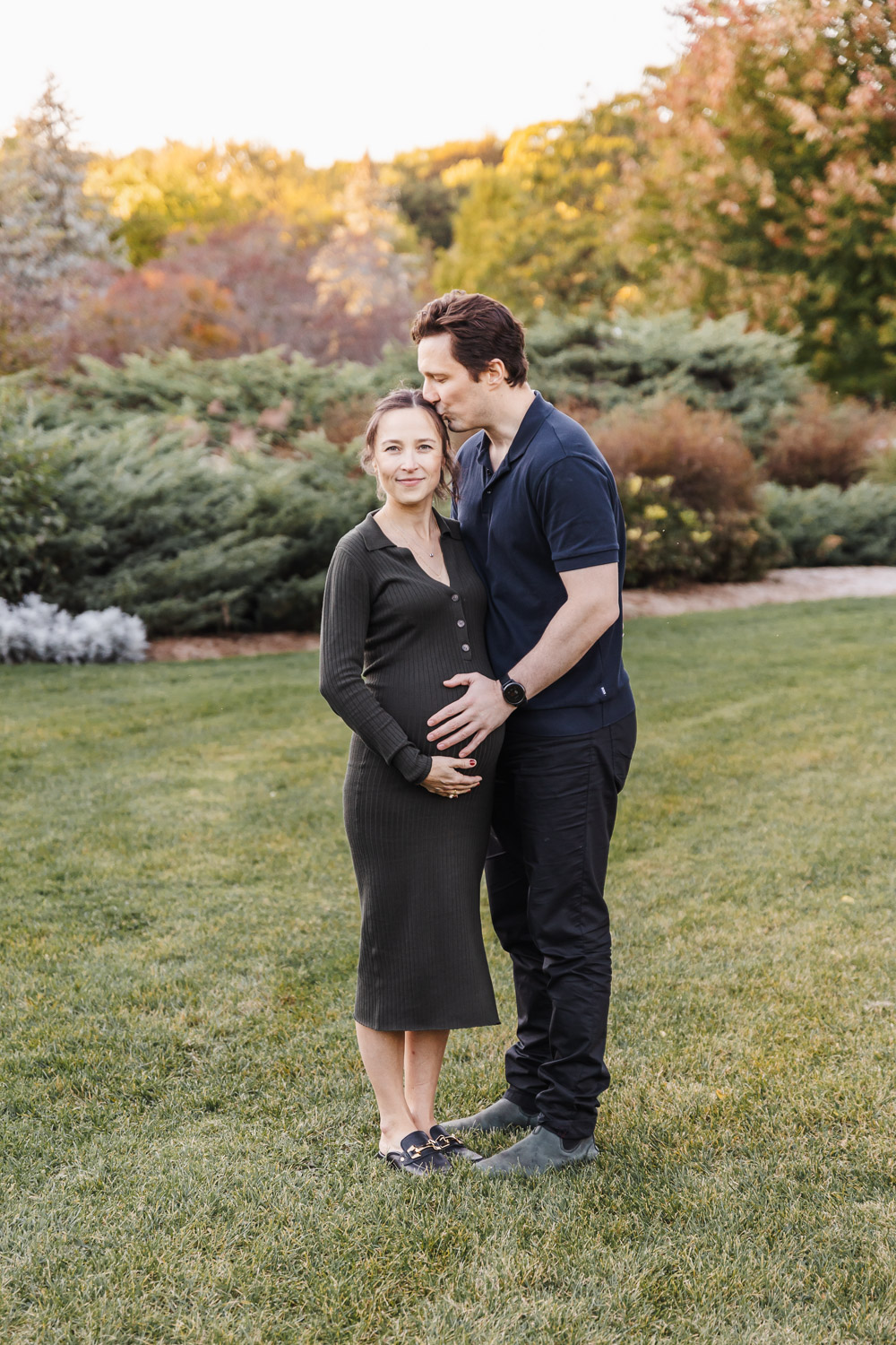 Man kissing pregnant wife during their family portraits in James Gardens