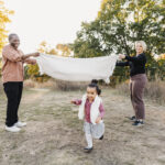 Preschool age girl running under blanket help up by her parents at High Park