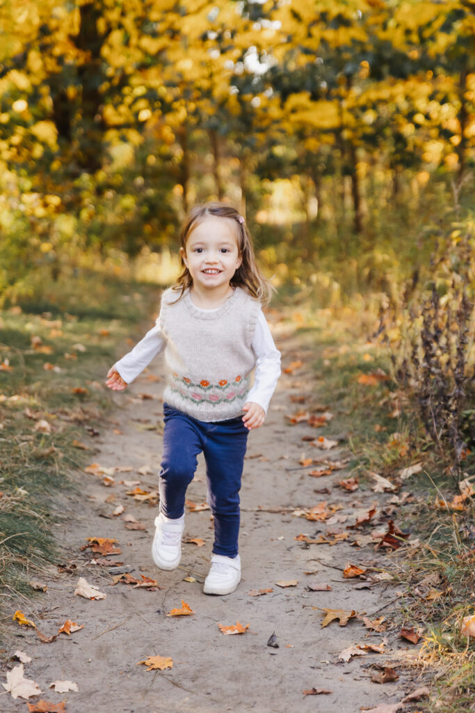 Toddler girl running on golden lit path in High Park