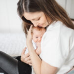 Mom of Helping hands doulas cuddling her new baby daughter