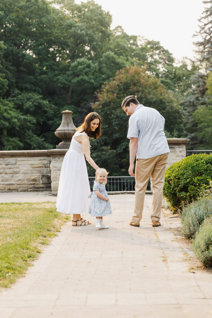 Summer Family Photos at Alexander Muir Memorial Gardens 12 Happy toddler girl walking with her parents during family photos at Alexander Muir Memorial Gardens