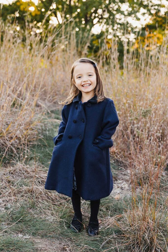 young girl dressed in navy jacket in park setting