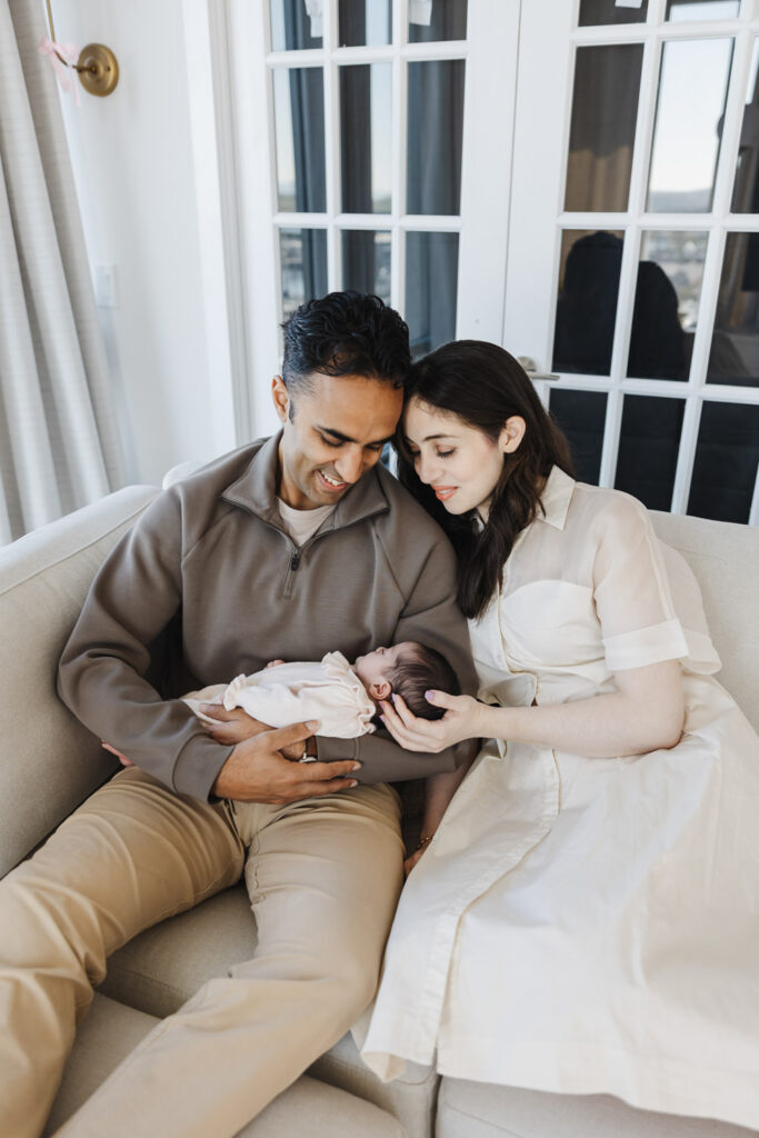 Couple holding newborn in cozy living room of downtown Toronto Condo during newborn photo session