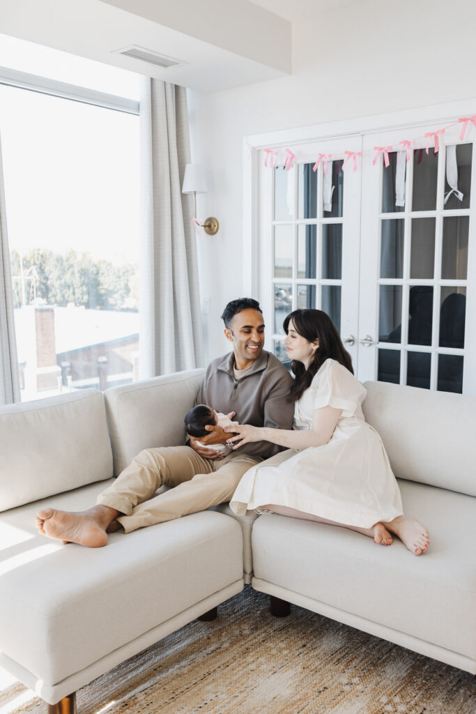 couple and newborn daughter on couch of Toronto condo captured during in-home newborn photos