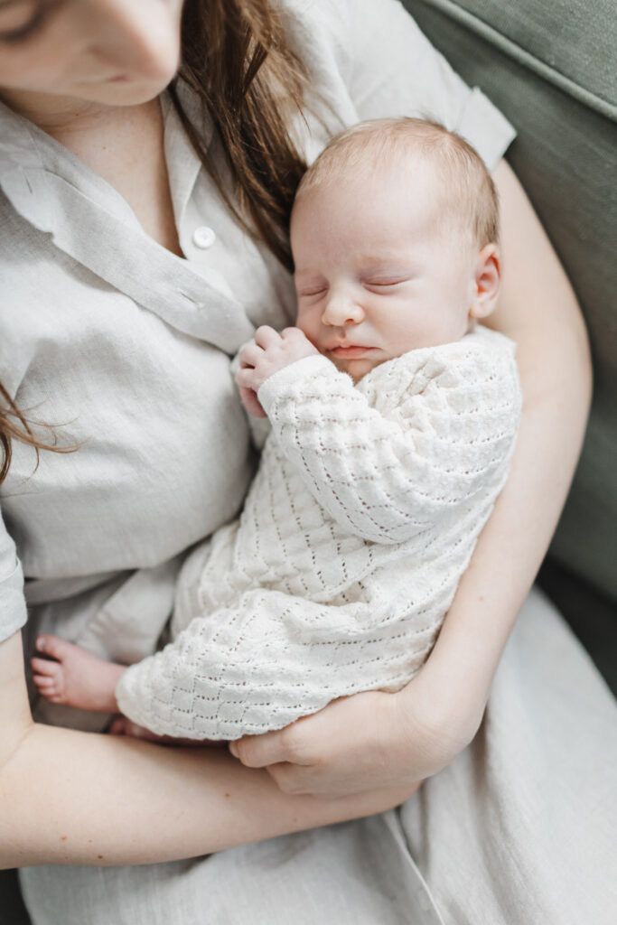 baby girl dressed in Zara knit romper cuddled by mom during toronto newborn photography session