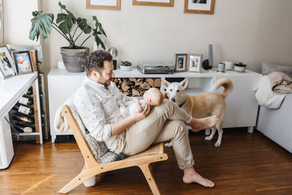 Dad dressed in casual button up shirt and khakis during at home newborn photos in Toronto