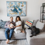 Family dressed in neutral colours hanging out in their living room during a Toronto newborn session