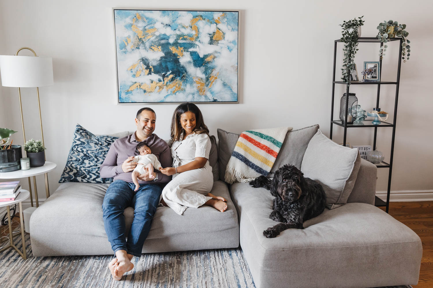 Family dressed in neutral colours hanging out in their living room during a Toronto newborn session