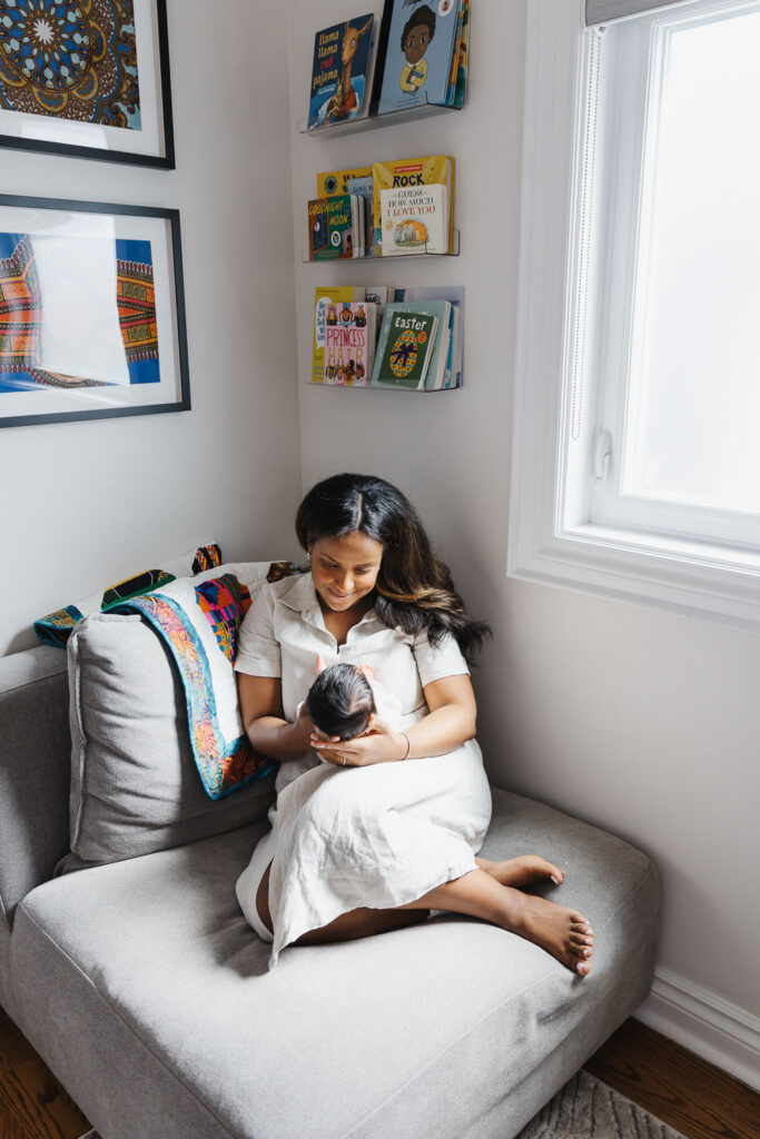 mom holding baby girl in Toronto home nursery captured during newborn photo session