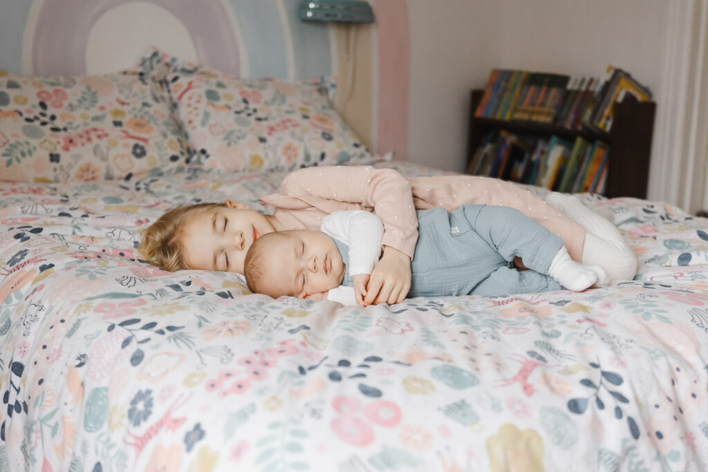 big sister cuddling with newborn baby brother during toronto at home newborn photo session